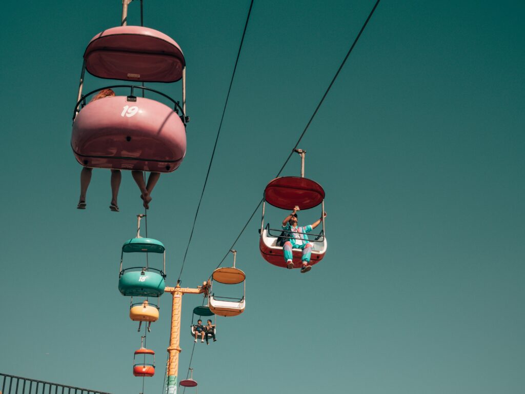 cable cars in the sky people riding green backround with colorful cars