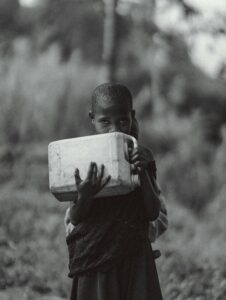 boy carrying water jug black and white